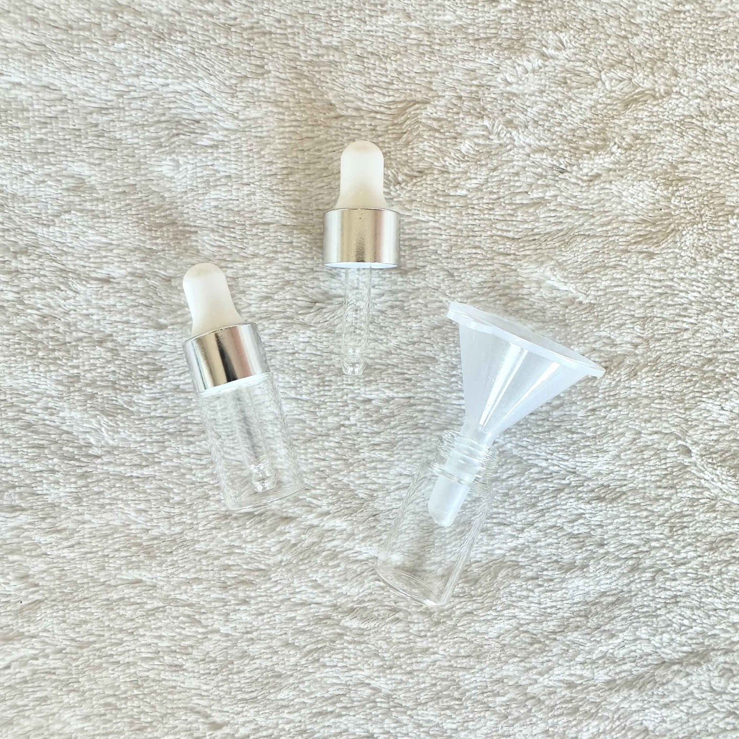 Two small anointing oil bottles with a funnel