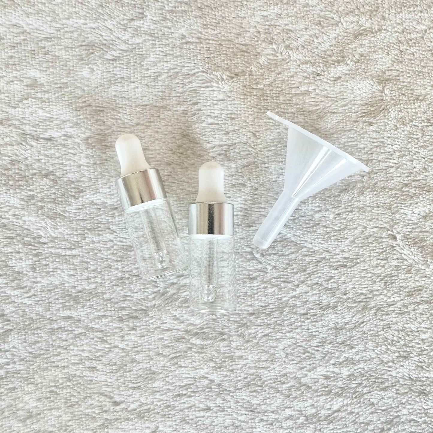 Two small anointing oil bottles with a funnel