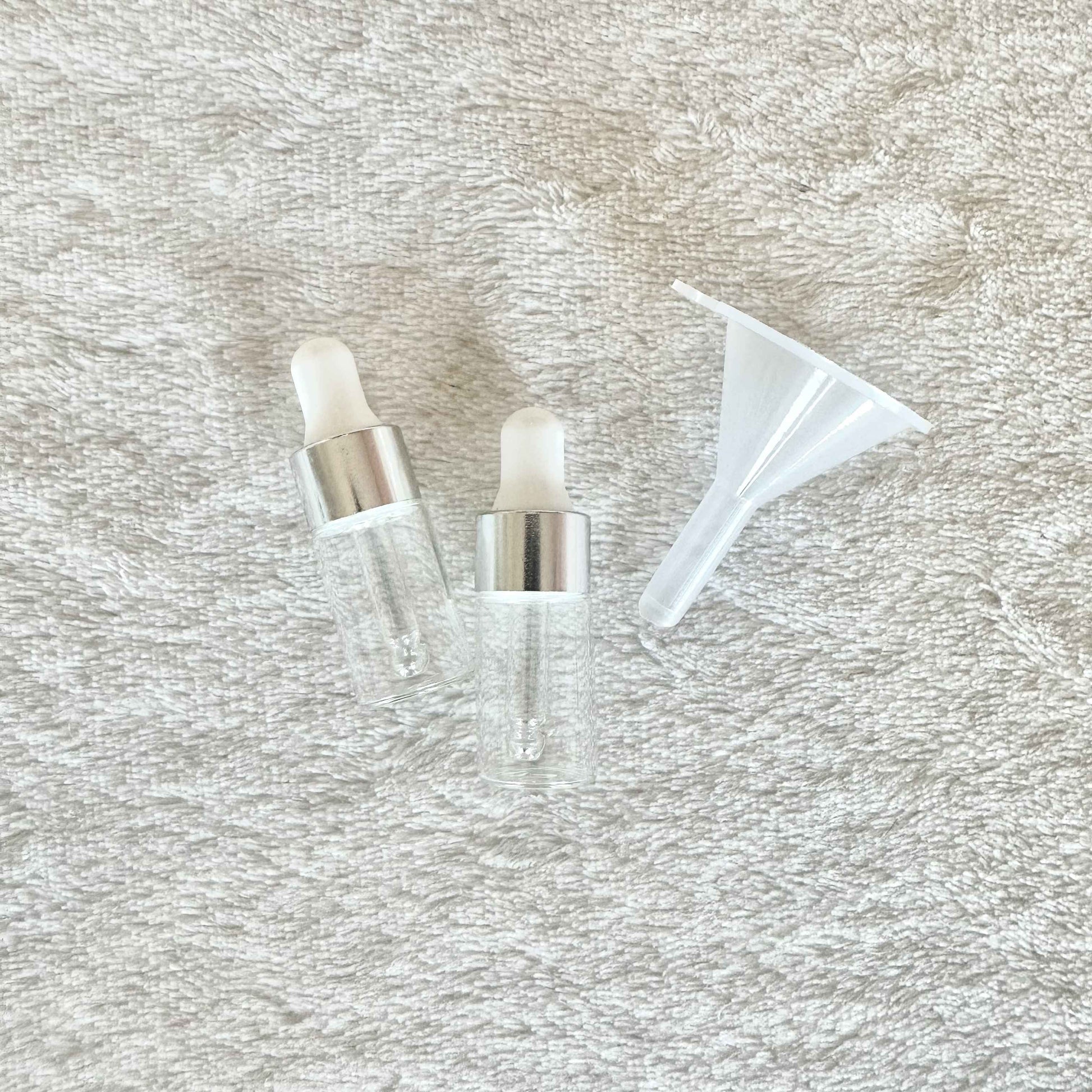 Two small anointing oil bottles with a funnel