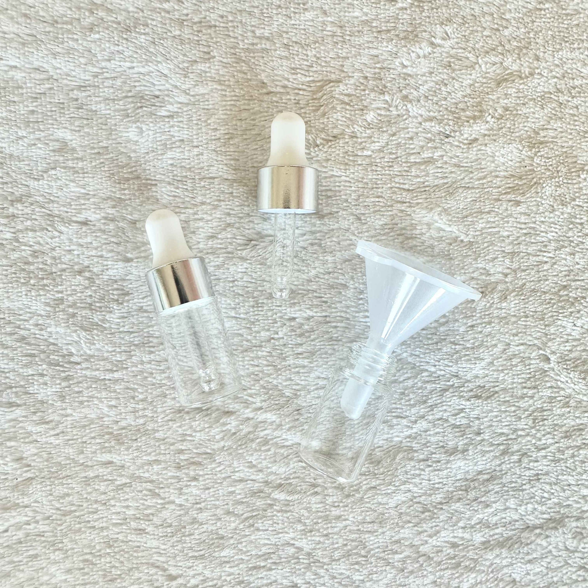 Two small anointing oil bottles with a funnel