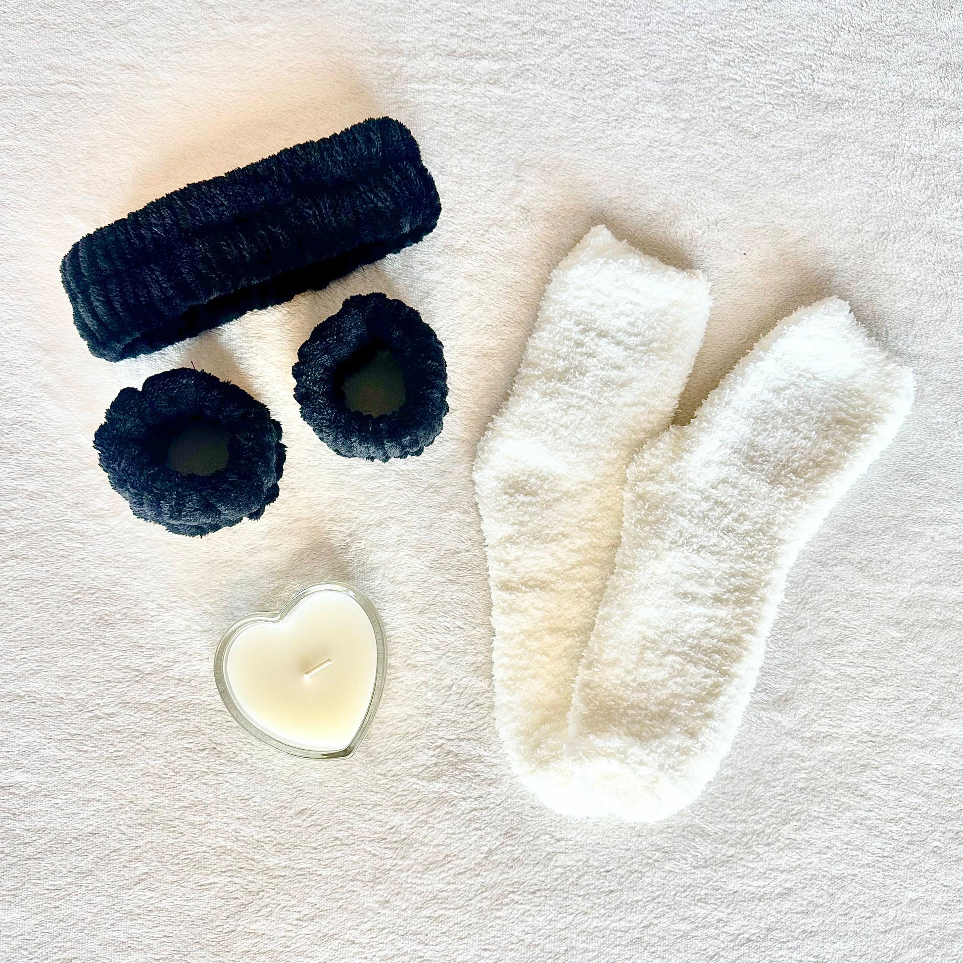 Gift set including skincare headband, pols bands, cozy thick socks, and heart-shaped candle