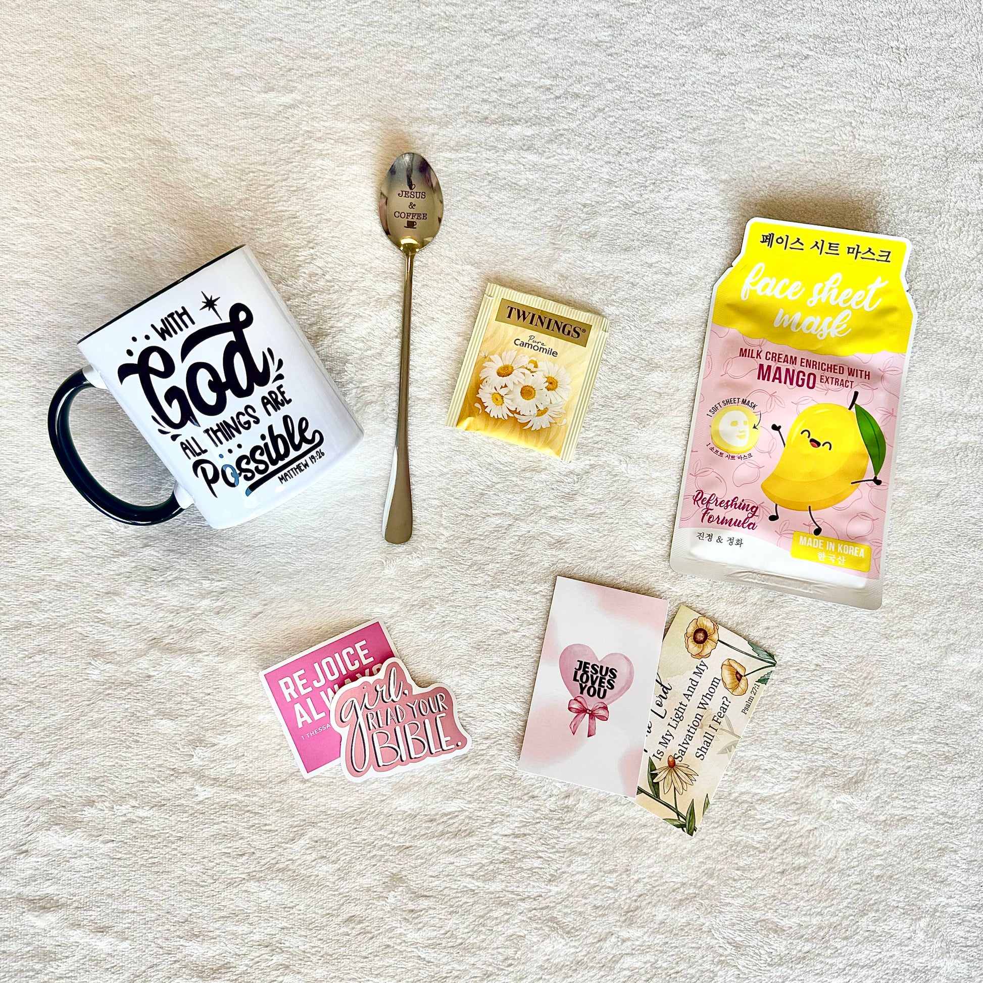 Gift set including a Korean sheet mask, a faith inspired mug, a bible verse inspired spoon, a Twinings tea pocket, christian stickers, and a bible verse card